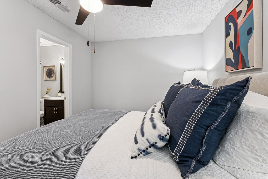Bedroom A bed with a grey blanket and a blue and white pillow.